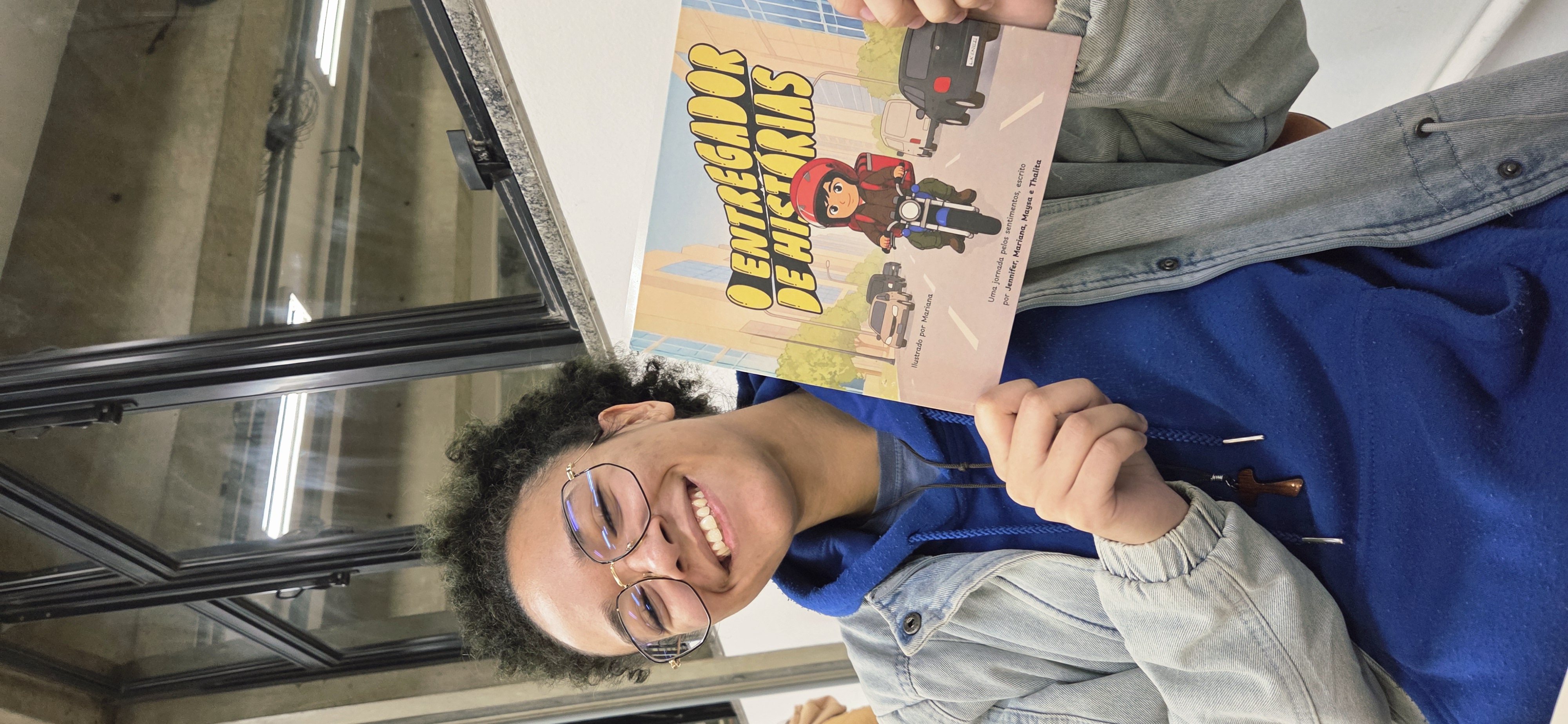 Mari segurando o livro impresso O Entregador de Histórias